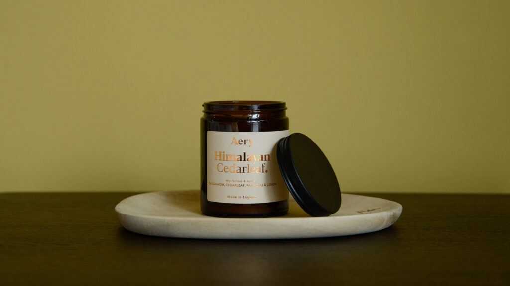 Aery Himalayan Cederleaf candle in glass jar on a tray with the lid balanced on the side.
