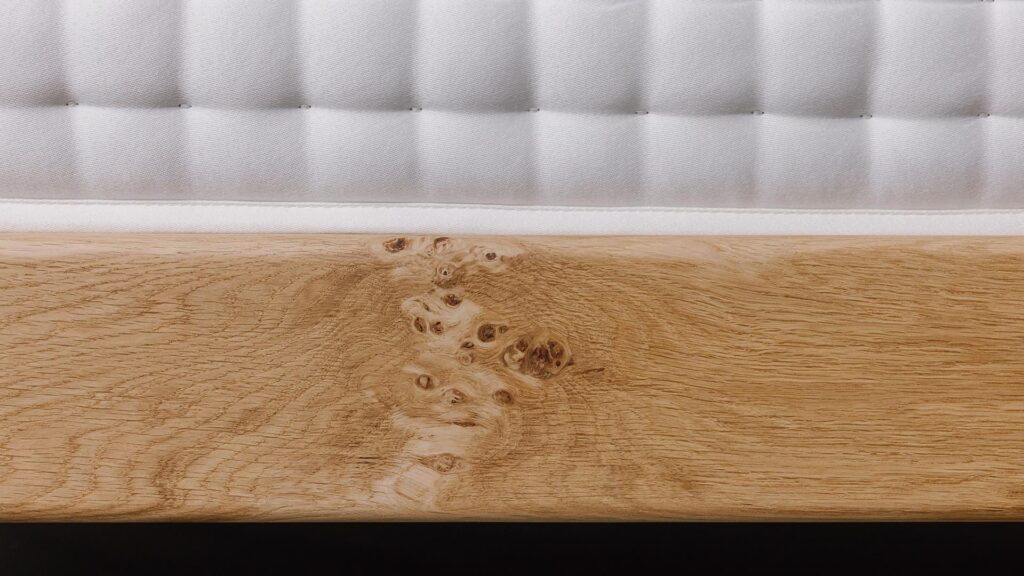 close up of knot detail on the side rail of an English oak bed frame.