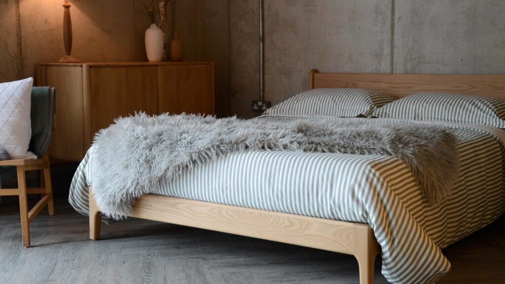 Image showing the faux afghan throw spread over the Pimlico bed, which is also dressed in green and white striped bed linen.