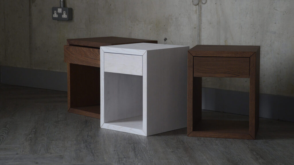 Image showing three small bedside tables. The tables are stained - one in a pale white shade and two in a dark brown colour, similar to walnut.