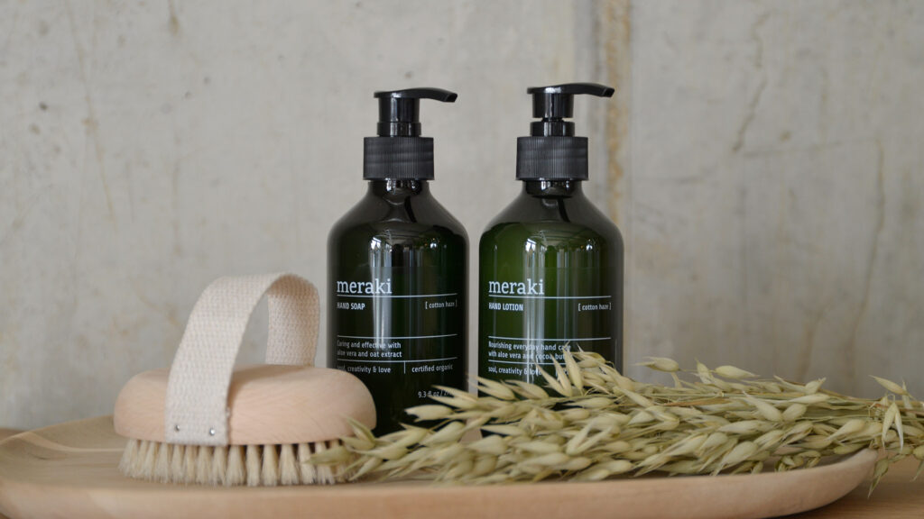 Bottles of hand soap and lotion photographed with nail brush on tray.