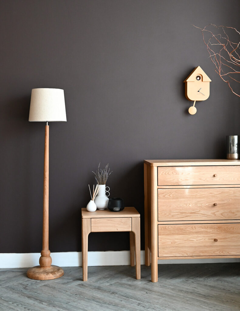Room set with wooden floor lamp, bedside table and chest of drawers.