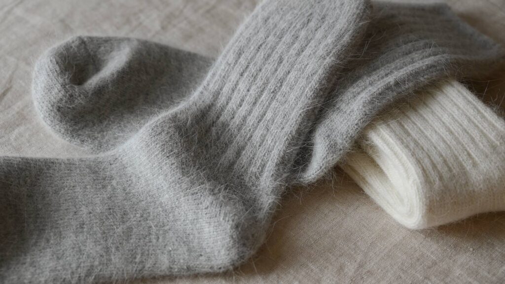 2 pairs of Angora blend socks with rib top. Ivory pair neatly folded, grey pair laid flat on top.
