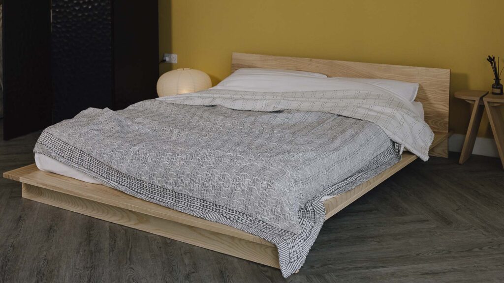 Grey Block print bedspread with wave design spread over the Oregon bed frame in ash.