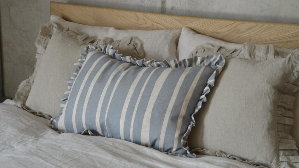 Blue cushion with ecru stripes and ruffled edges.