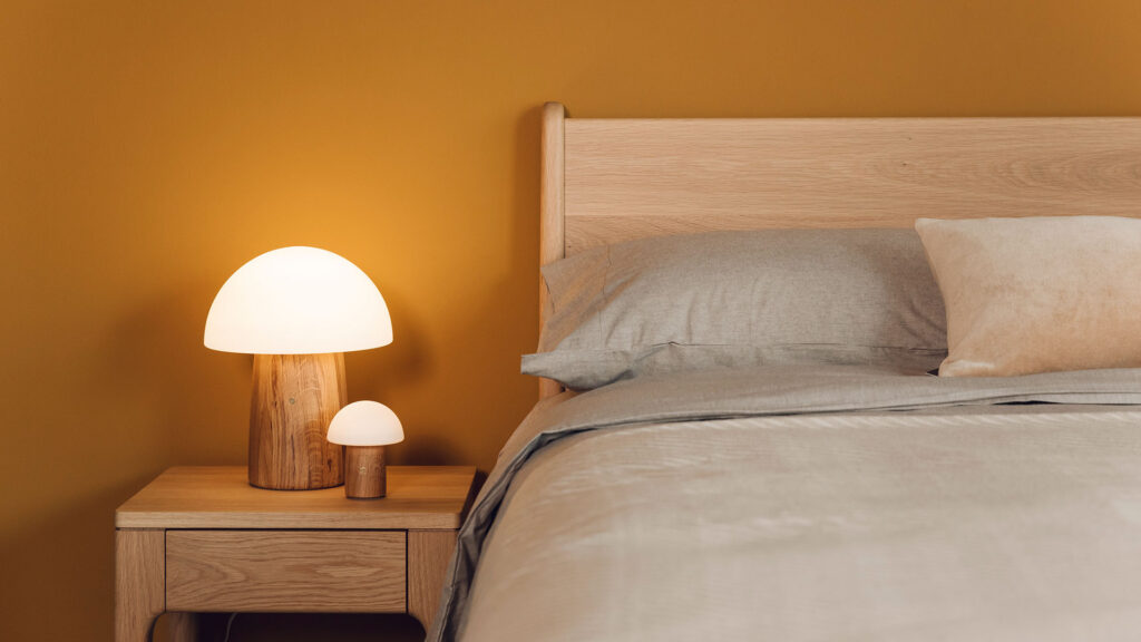 Oak camden bed with mushroom lamps and organic cotton bedding against yellow wall.