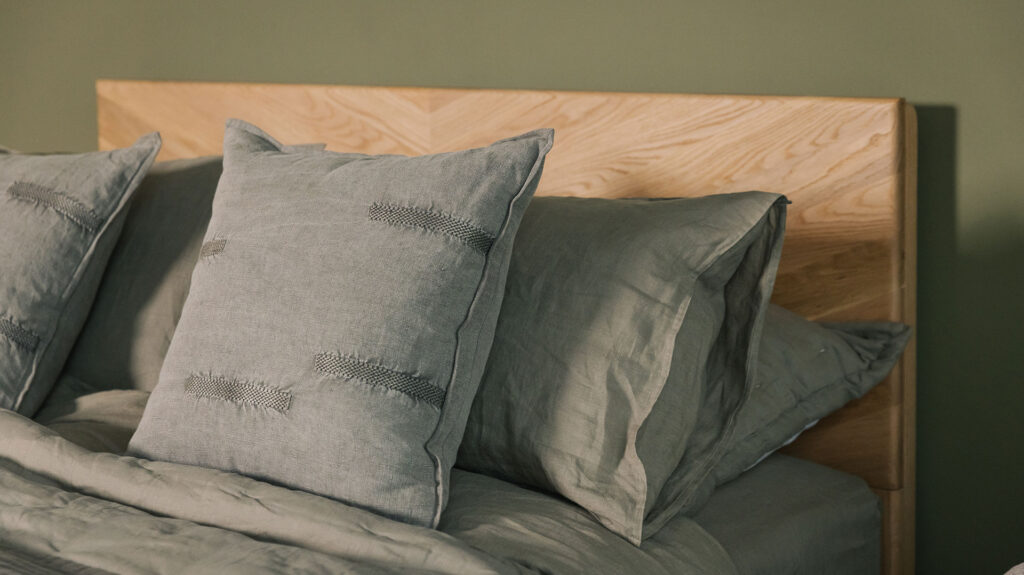 olive green stitched cushions shown on a bed