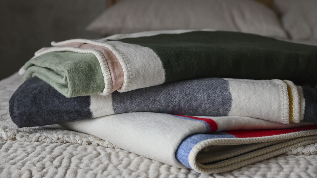 Stack of three neatly folded throw with abstract designs.