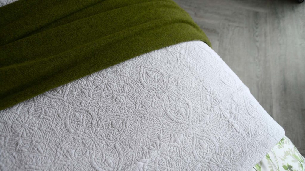 embroidered bedspread in white with green throw
