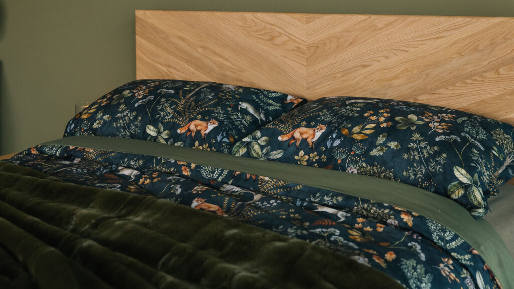 Dark green duvet cover and pillowcase set with a nature print of foxes, plants, and owls