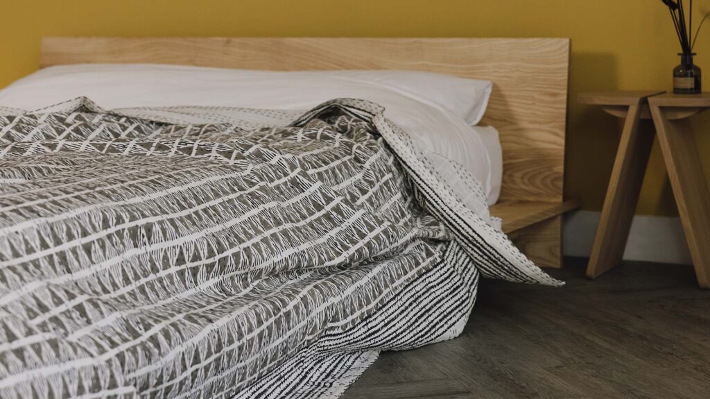 Grey block print bedspread with triangle pattern.