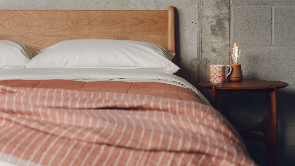 mid century bedroom style with a low cherry wood Carnaby bed and rich curvy mahogany side table