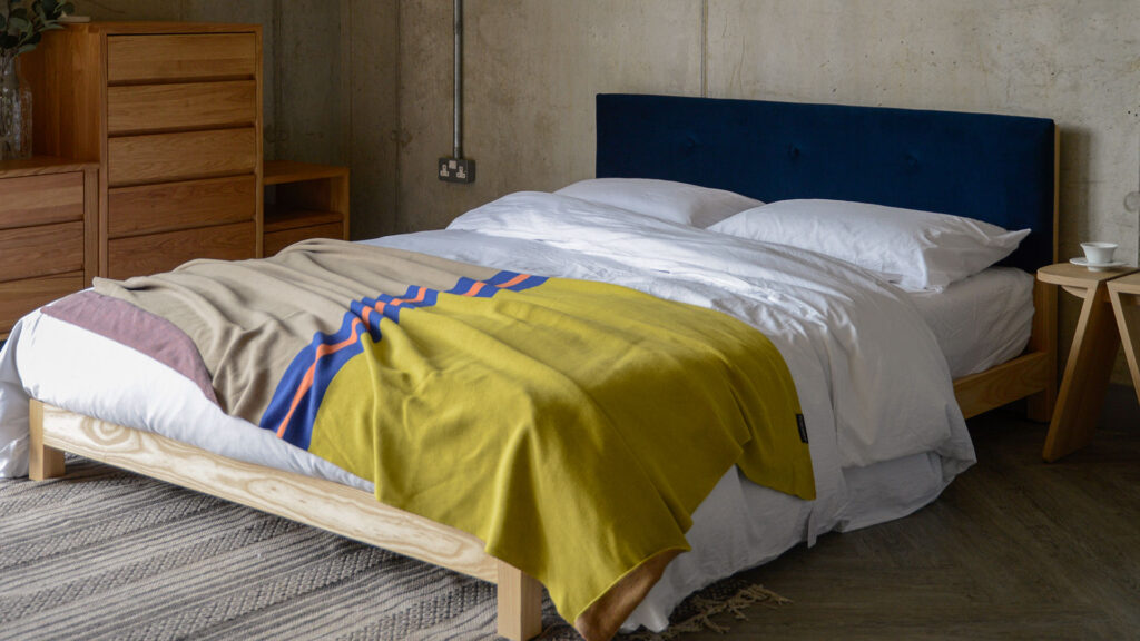 iona with white bedding colourful knit blanket