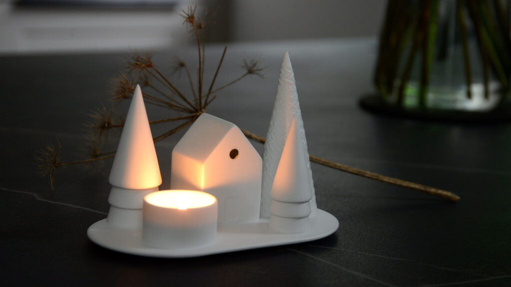 Snowy scene matt porcelain tea light holder with trees and a house shown lit