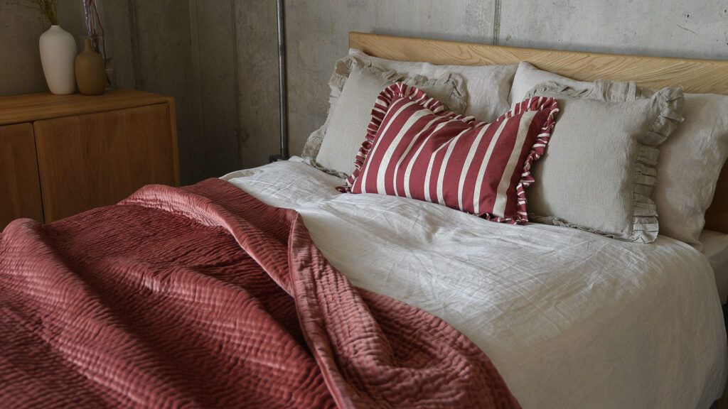 Oak bed frame with ecru and wine bedding.