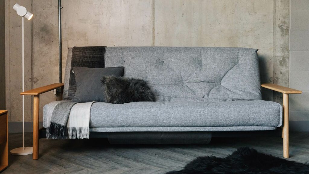 mid century look sofa bed with solid oak arms shown with grey cover