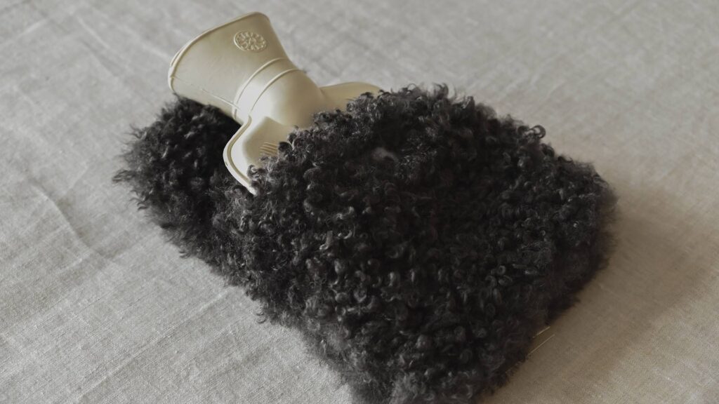 Mini hot water bottle with dark brown faux fur cover.
