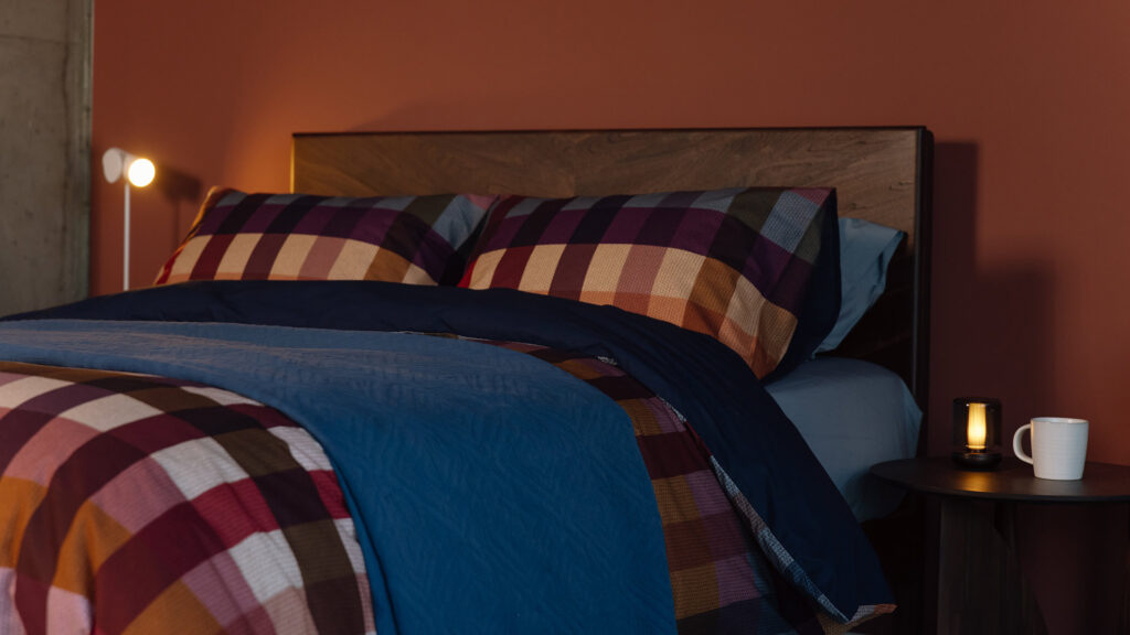 multicolour check bedding topped neatly with a deep blue diamond print bedspread.