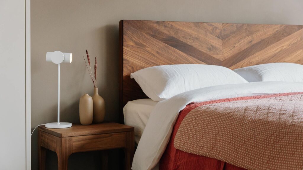 oiled walnut bed with white linen and rose bedding and white lamp