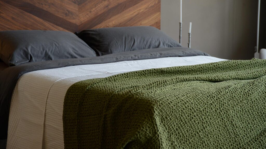waffle weave cotton throw in an olive green colour shown on a kingsize bed