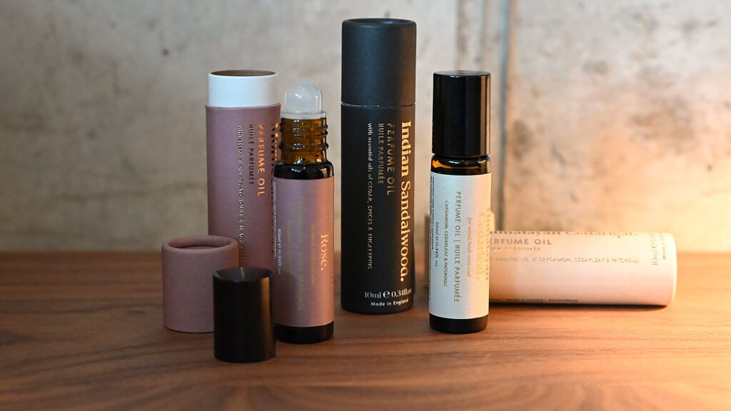 Perfumed oils standing on wooden surface. Packaging also displayed.