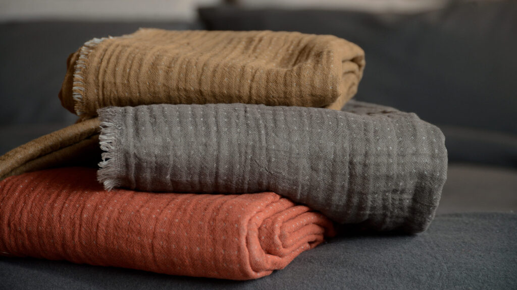 reversible cotton throws stack tan grey and rust