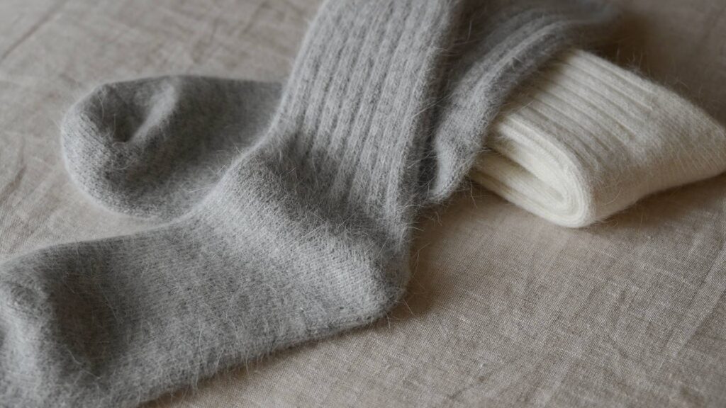 2 pairs of Angora blend socks with rib top. Ivory pair neatly folded, grey pair laid flat on top.