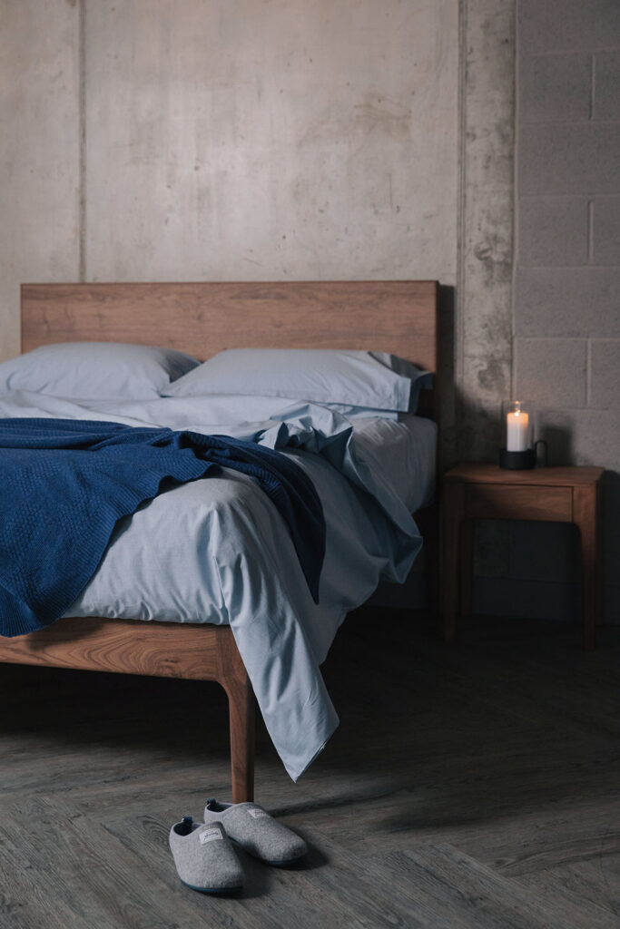 walnut bed and bedside table with blue bedding portrait