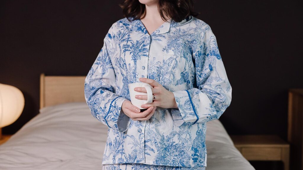 model wearing blue and white jungle print pyjamas holding a mug.