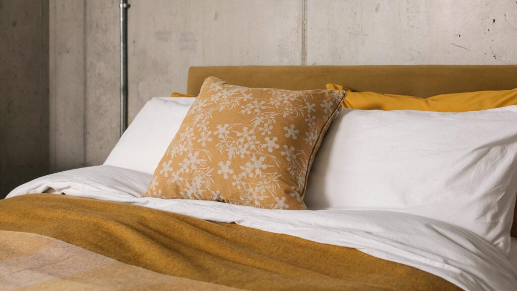 white stonewashed cotton bedding and ochre floral cushion